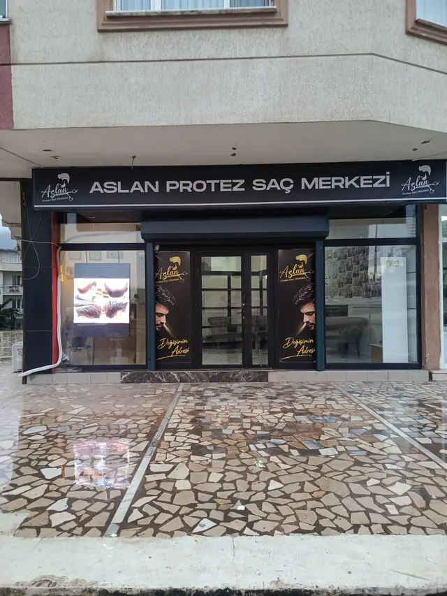 Apartmanın zemin katında, siyah tabelalı Aslan Protez Saç Merkezi cephesi